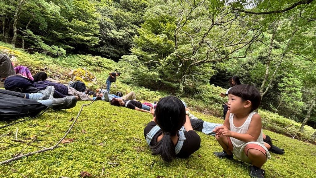 苔の広場で寝転び、くつろぐ参加者と子どもたち
